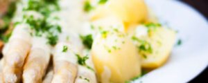 Köstlicher weißer Spargel und Kartoffeln übergossen mit Sauce hollandaise, glatter Petersilie und Safran