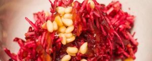 La belle salade de légumes crus pourpre servie dans un plat avec des pignons de pin supplémentaires